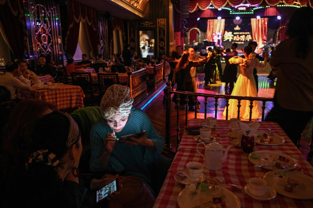 A woman looks at her mobile phone while couples are dancing at the Paramount Ballroom in the Jing’An district of Shanghai December 11, 2025. — AFP pic