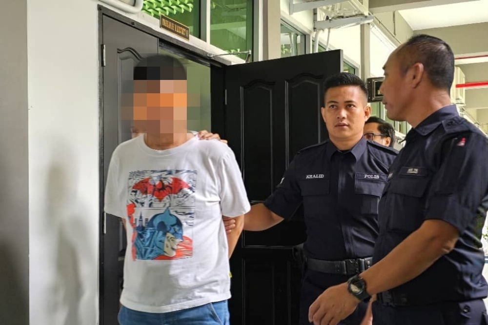 One of drug-trafficking case suspects being escorted out of the courtroom following the proceedings. — The Borneo Post pic