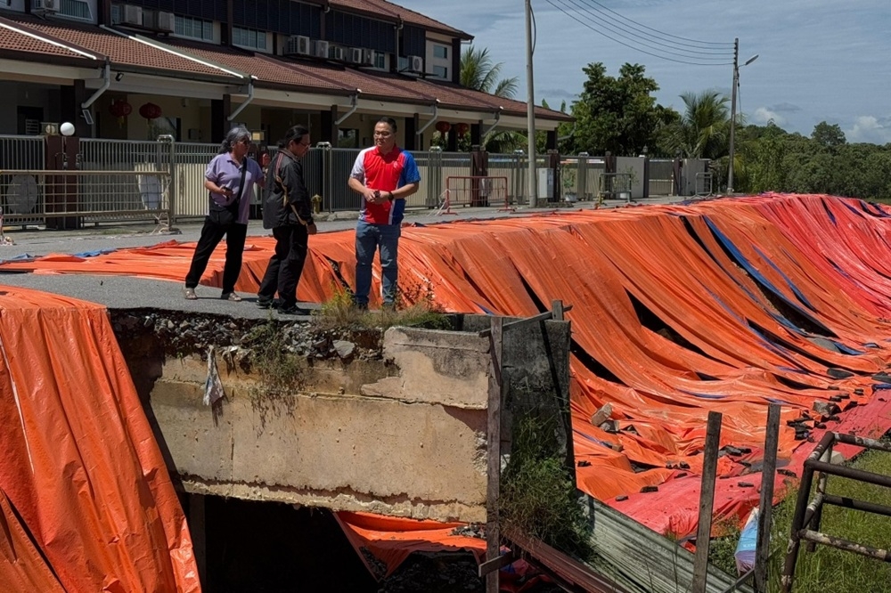 DAP Sarawak committee member Stanley Chiew (right) inspects areas affected by the landslide. — The Borneo Post pic