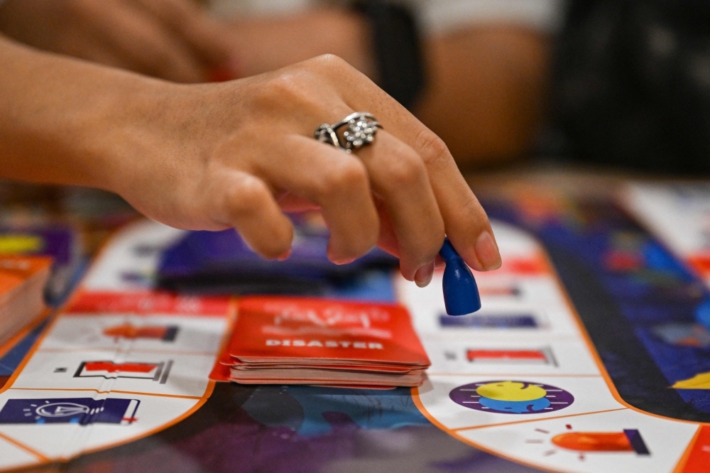 This photo taken on December 9, 2025, shows participants playing Master of Disaster, a board game about disaster preparedness, at a library in Valenzuela, Metro Manila. — AFP pic