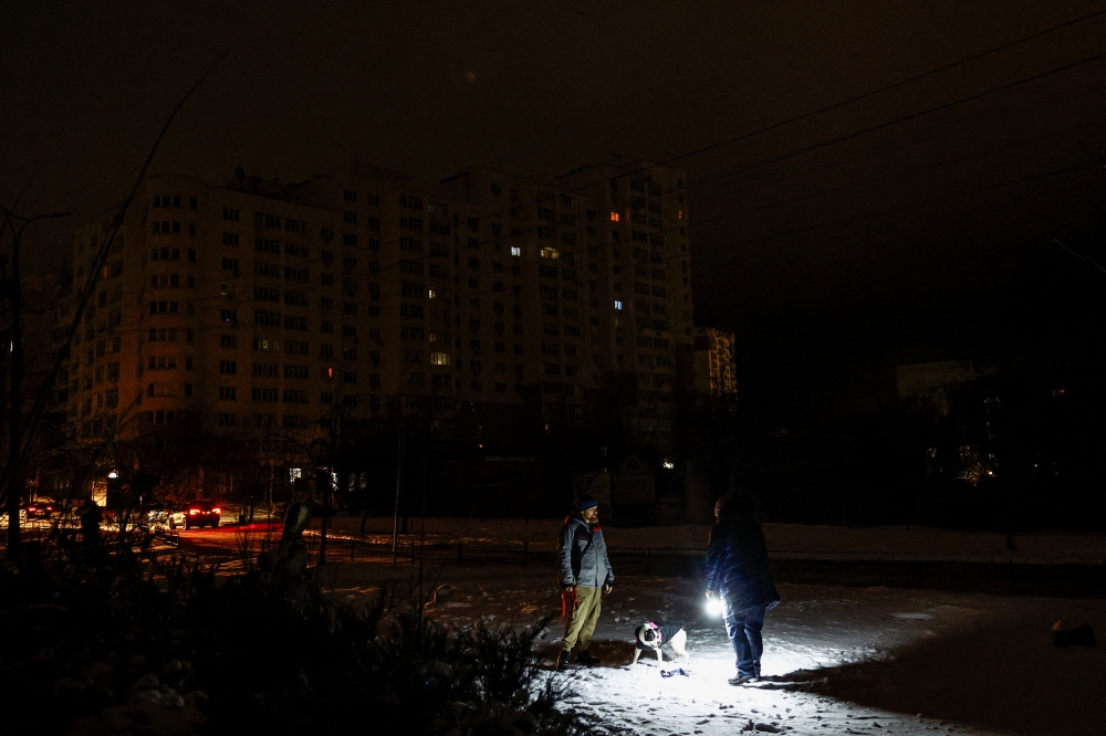 Residents play with a dog in a park in the town of Vyshhorod during a long power blackout after critical civil infrastructure was hit by a Russian missile and drone strikes, in Kyiv region, Ukraine, December 29, 2025. — Reuters pic