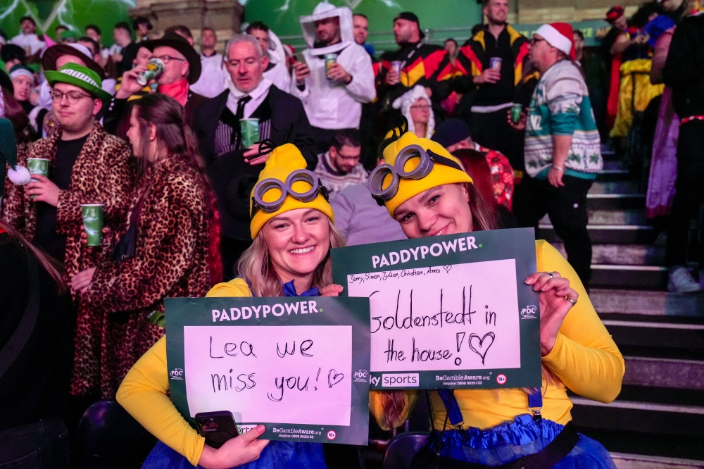 Two spectators dressed up as Minions pose for a photograph  holding placards with messages during the World Darts Championship at Alexandra Palace in London December 28, 2025. — AFP pic