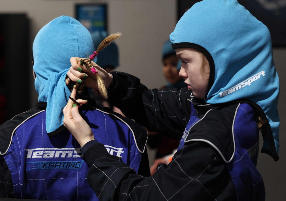 A girl makes a fellow driver’s hair safe before participating in a TeamSport Go Karting girl only taster session in Nottingham October 29, 2025. — AFP pic