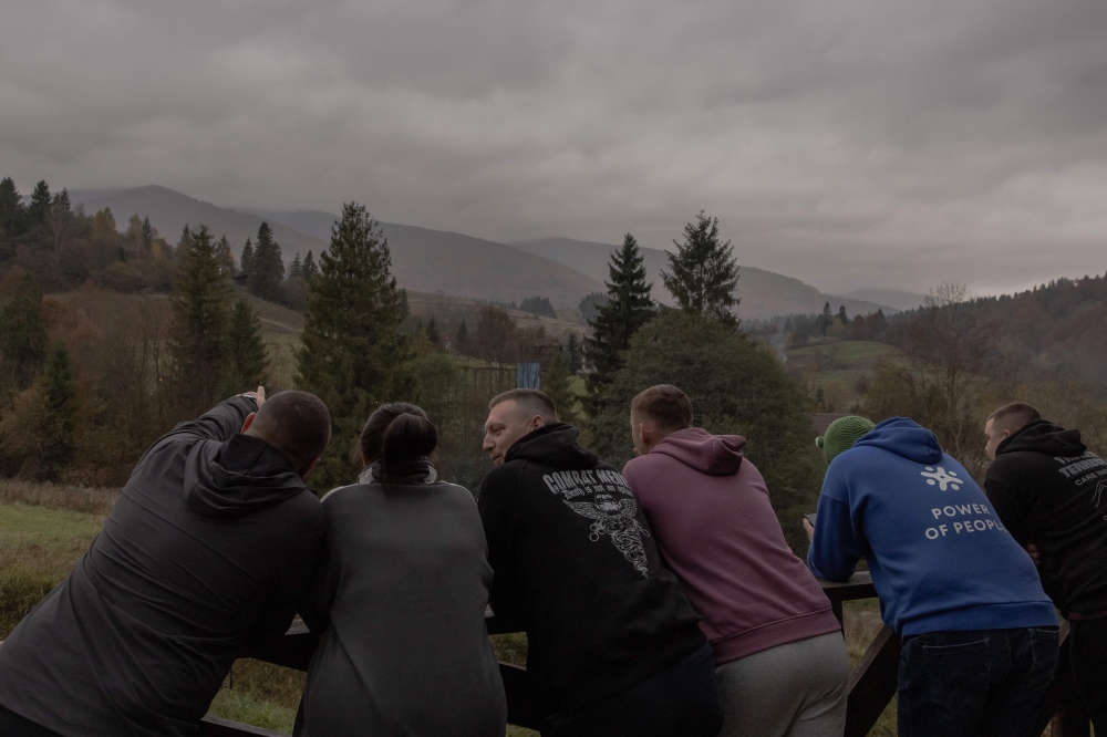 Ukrainian military medic Roman Zukh (centre) chat with other military medics as they look out at the mountains at the RePower programme, a mountain retreat designed to support their psychological recovery and mental well-being in Ukraine's western Zakarpattia region on October 23, 2025, amid the Russian invasion of Ukraine. — AFP pic