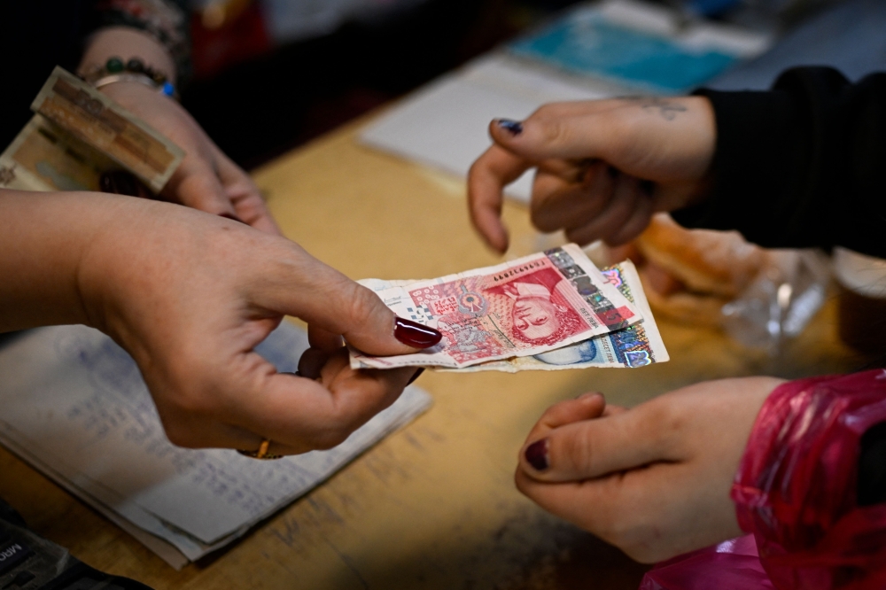 A grocery store owner returns lev banknotes to a customer in a grocery store in the village of Chuprene, northwestern Bulgaria on December 7, 2025. — AFP pic