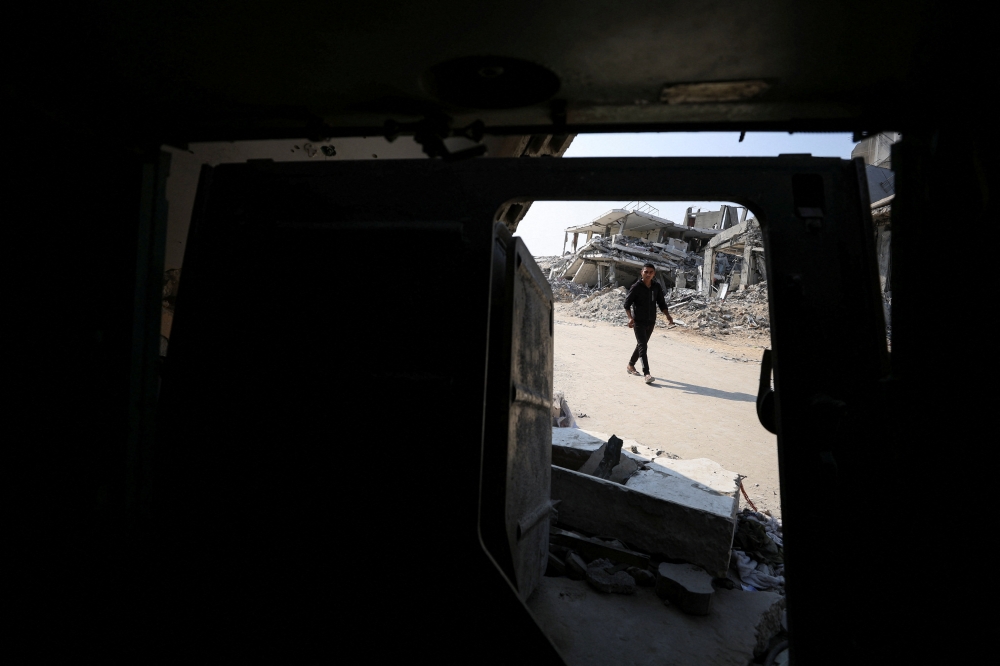 A Palestinian walks next to an armoured personnel carrier and destroyed buildings after Israeli military operations in Gaza City, November 7, 2025. — Reuters pic