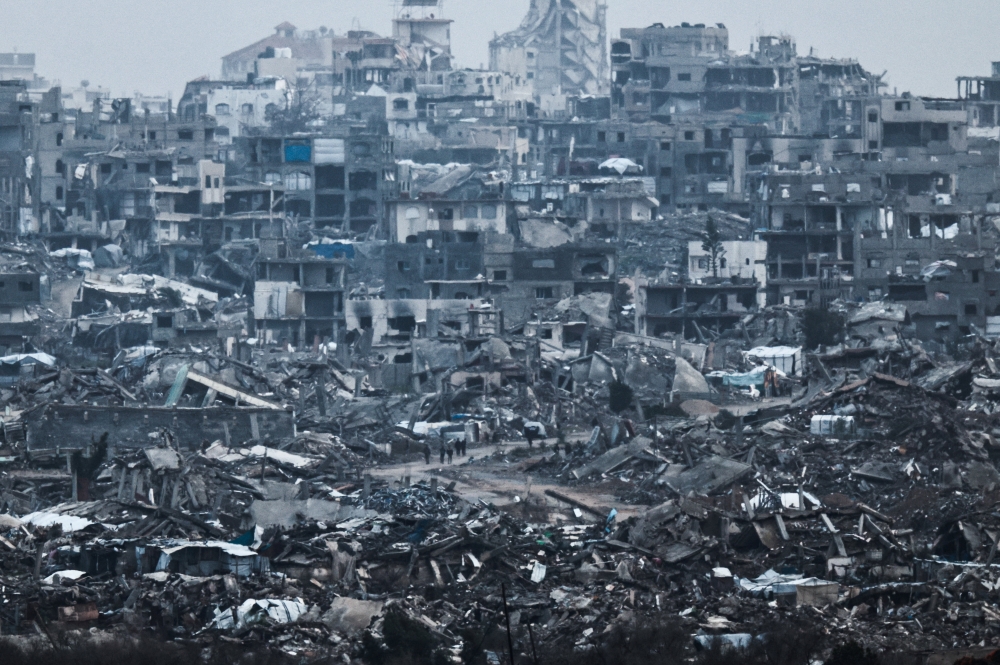 Palestinians walk near damaged buildings in the Gaza Strip, as seen from Israel's border with Gaza December 29, 2025. — Reuters pic