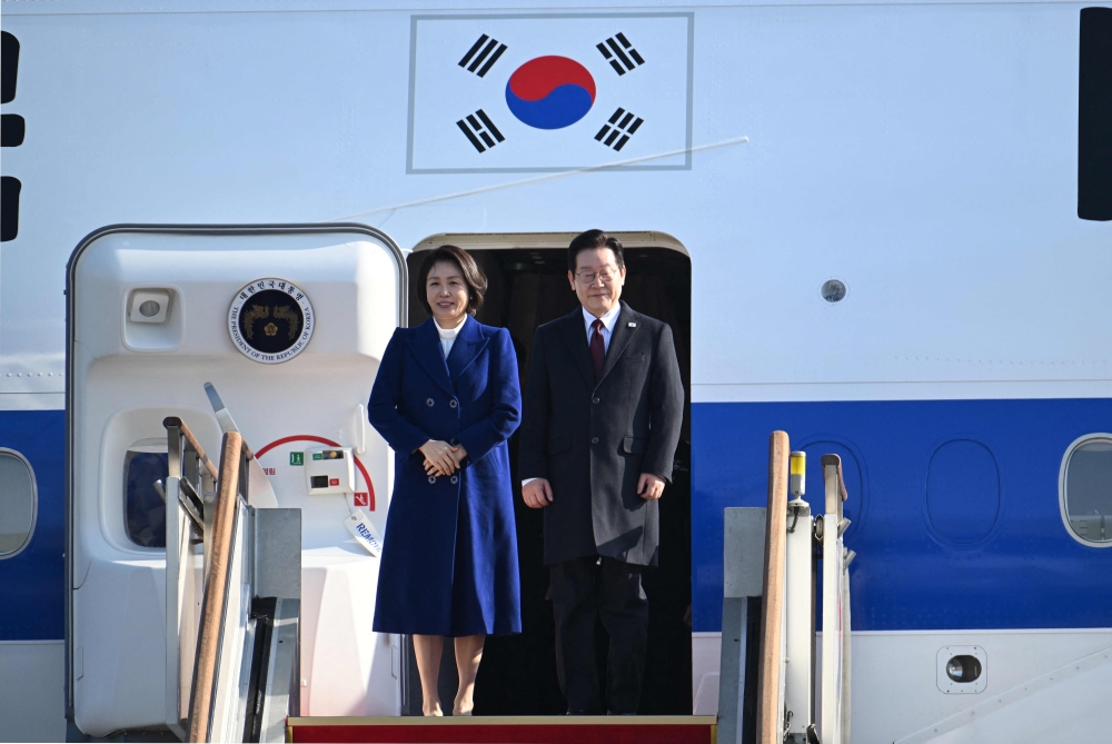 South Korea President Lee Jae Myung (right) and his wife Kim Hea Kyung (left) board their plane to depart for China at Seoul Air Base in Seongnam on January 4, 2026. — AFP pic