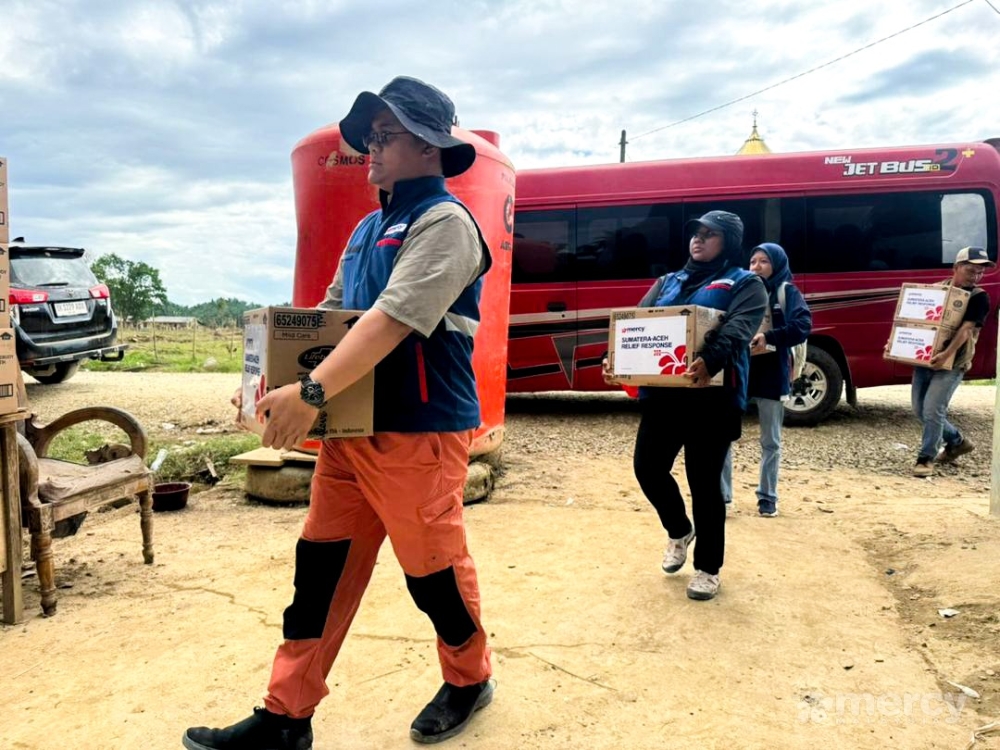 Aid workers distribute essential supplies to flood-affected families in Aceh under a humanitarian programme led by Malaysia. — Picture via Facebook/Mercy Malaysia