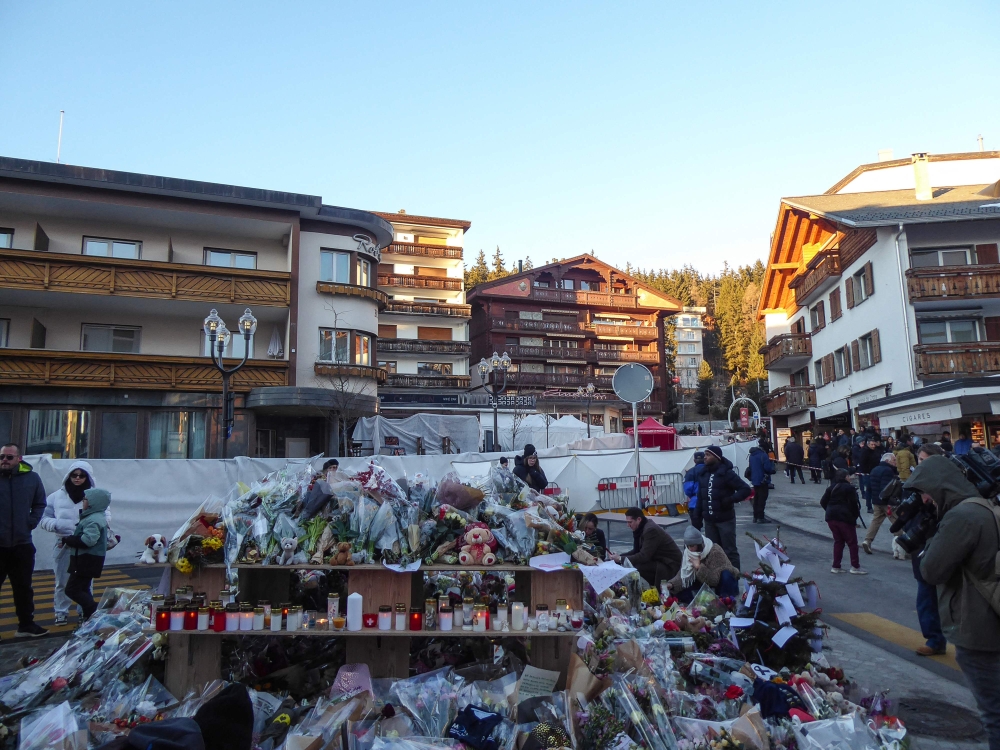 Mourners stand at a memorial set up in front of a blocked-off zone outside the ‘Le Constellation’ in the Alpine ski resort town of Crans-Montana, on January 3, 2026 after a NYE fire that killed 40 people. Investigations into the cause are ongoing. — AFP pic