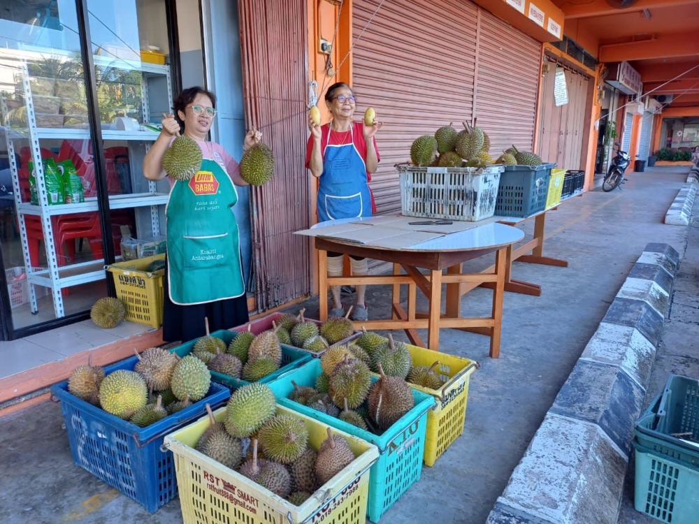 Two customers show off the durians they bought from Brainman Farm. — Picture via Facebook/Mujan Lah