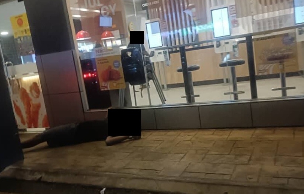 A man is seen collapsed near a fast-food outlet in Banting, Kuala Langat, following a suspected shooting late last night. — Picture from social media