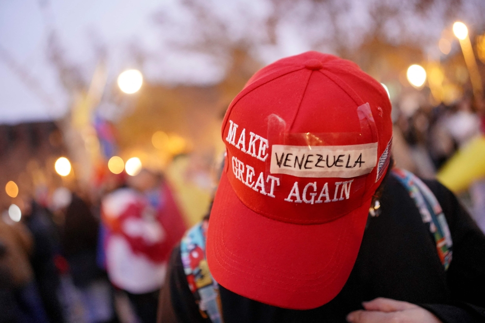 A protester wears a modified “Make America Great Again” hat with “Venezuela” taped over the original text during a demonstration in Barcelona on January 4, 2026. — AFP pic
