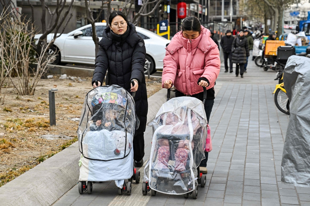 Women push baby strollers as they walk along a street in Beijing on January 4, 2026. — AFP pic