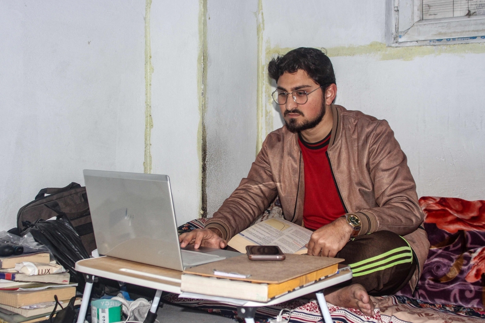 Shah Faisal, a Pakistani national studying at an Afghan university, uses his laptop at his residence in Jalalabad on December 29, 2025. — AFP pic