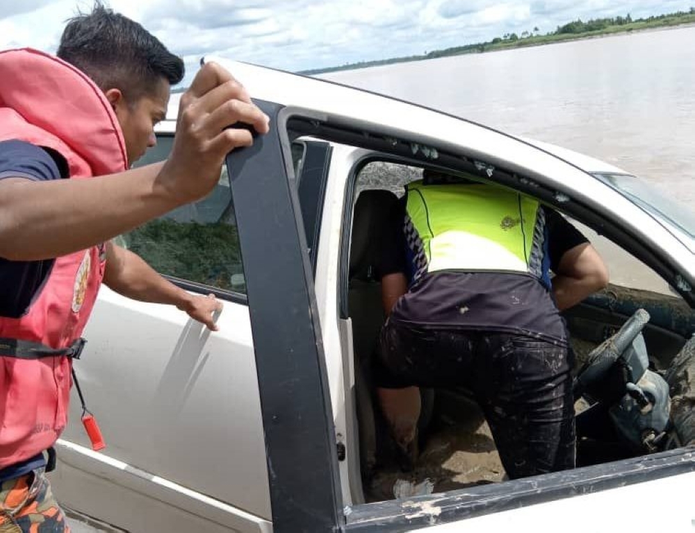 Bomba and police personnel search the vehicle for clues after it had fallen into the river, with the driver still missing. — Bomba pic