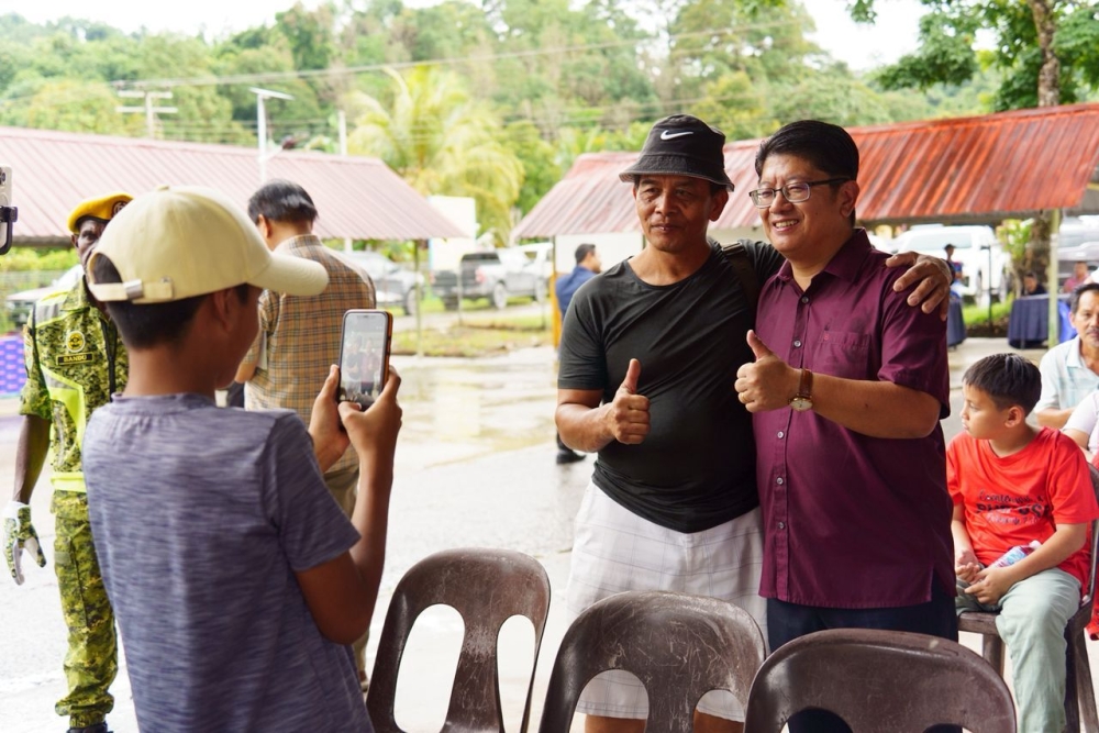 Ewon (right) joins a guest in a photo-call at the event in Kota Belud. — The Borneo Post pic