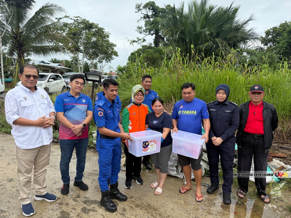Fatimah (4th left) witnesses the distribution of food baskets to a flood-affected family in Dalat. — The Borneo Post pic