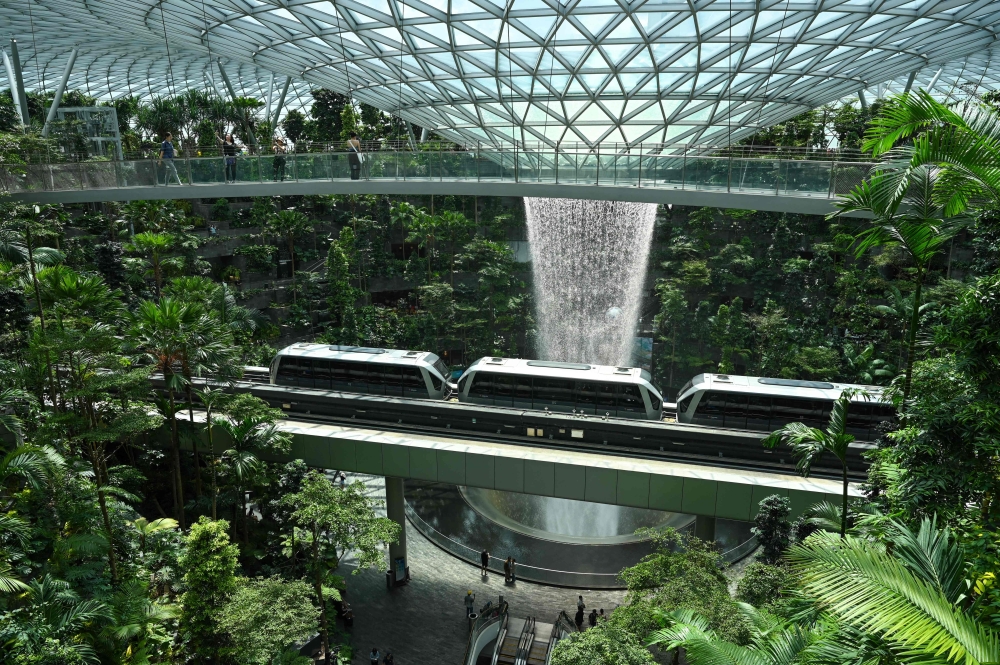 This file picture shows visitors photographing the Rain Vortex from an observation bridge as a train passes through Jewel Changi Airport in Singapore. — AFP pic