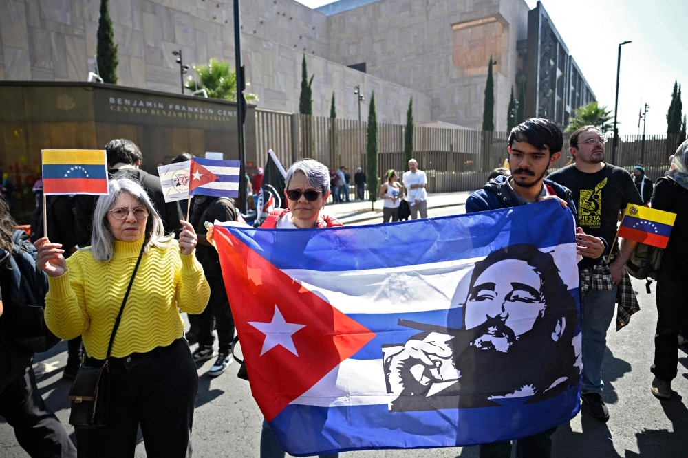 Members of social organisations protest against the US military operation in Venezuela with a Cuban flag depicting the late Fidel Castro in Mexico City on January 3, 2026. — AFP pic