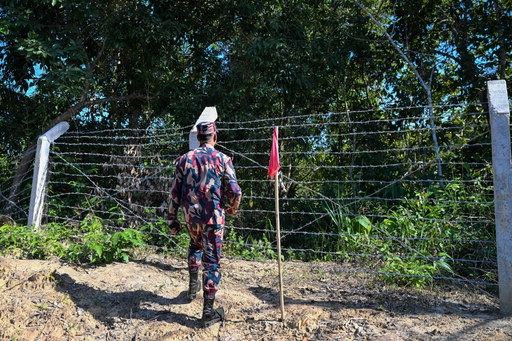 A Border Guard Bangladesh personnel inspects a red-flagged zone identified as a landmine risk area in the Bandarban frontier district on December 19, 2025. — AFP pic