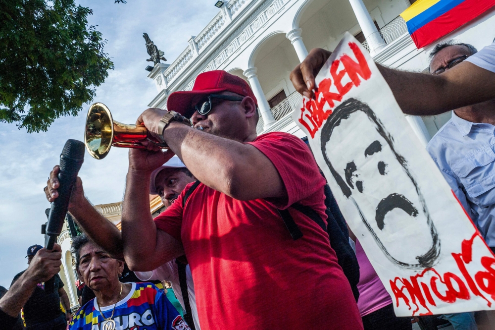 A supporter of ousted Venezuelan President Nicolas Maduro plays a trumpet during a demonstration while watching a session of the National Assembly on a big screen in Maracaibo, Venezuela on January 5, 2026. — AFP pic