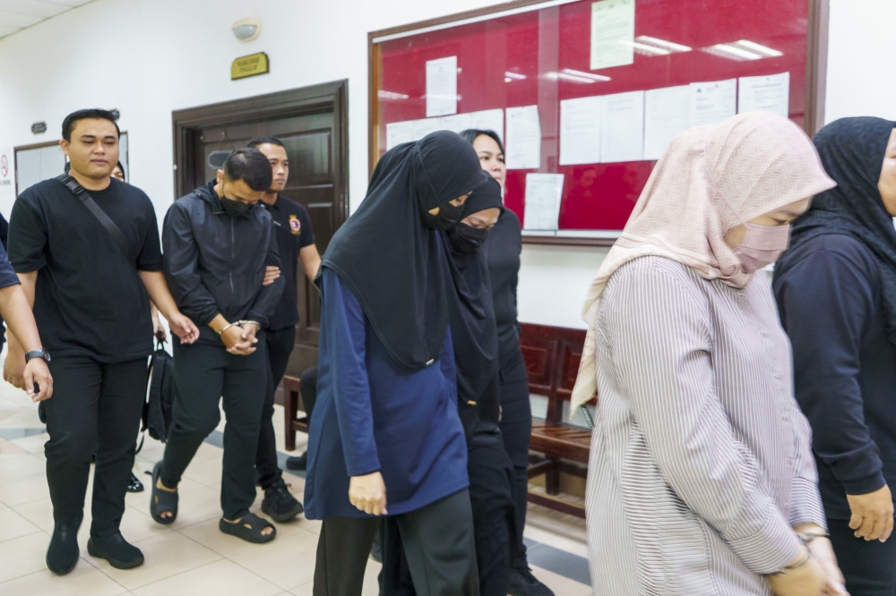 Three bank officers, all seen wearing face masks, were produced at the Sessions Court to face new cheating charges involving a total of RM600,000 from three alleged victims. — The Borneo Post pic