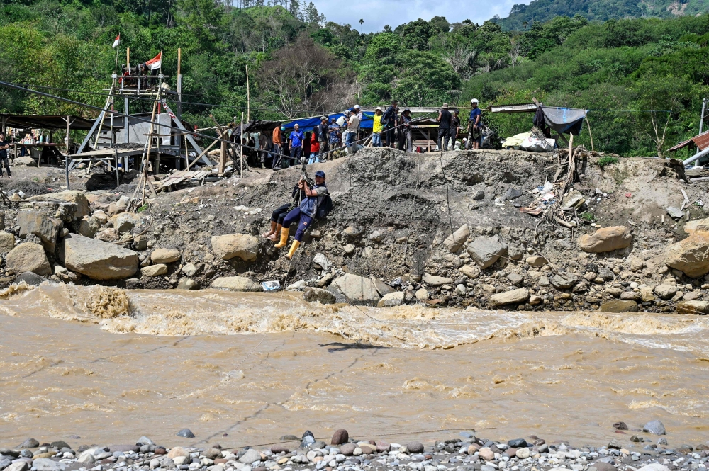 People use a rope to cross a river after flash floods destroy adjacent villages in Ketol, Aceh highland province, Indonesia on January 6, 2026. — AFP pic