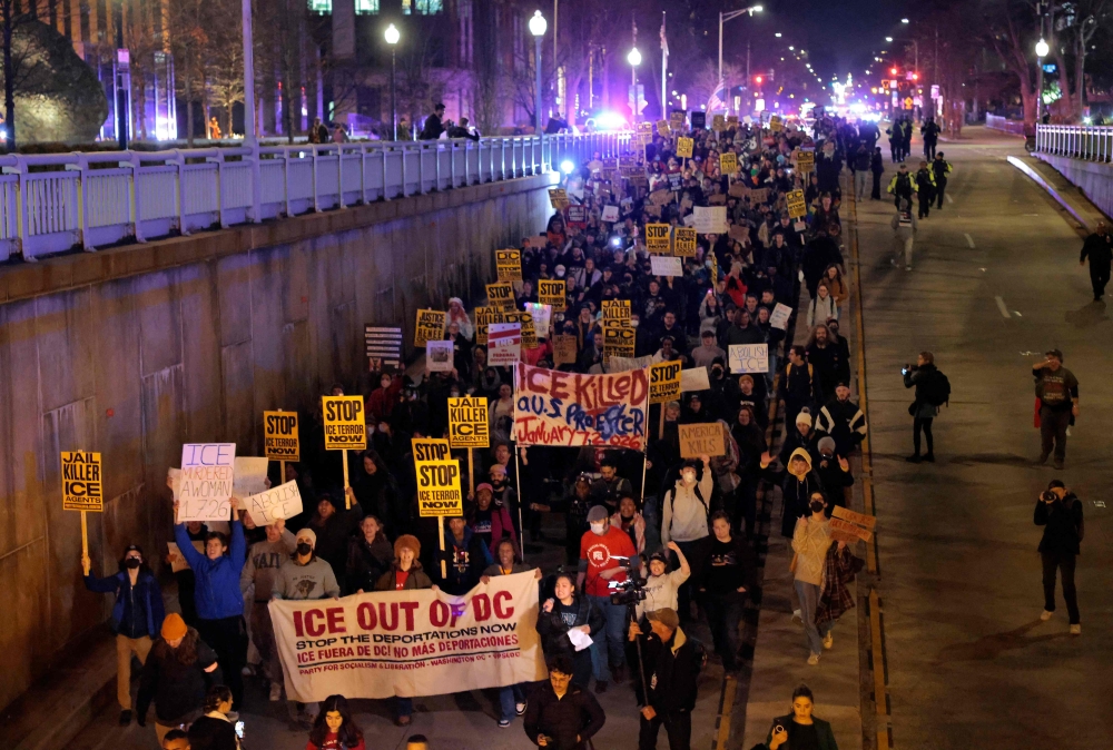 People hold signs as they march during a protest against the shooting death of Renee Nicole Good on January 8, 2026 in Washington, DC. — AFP