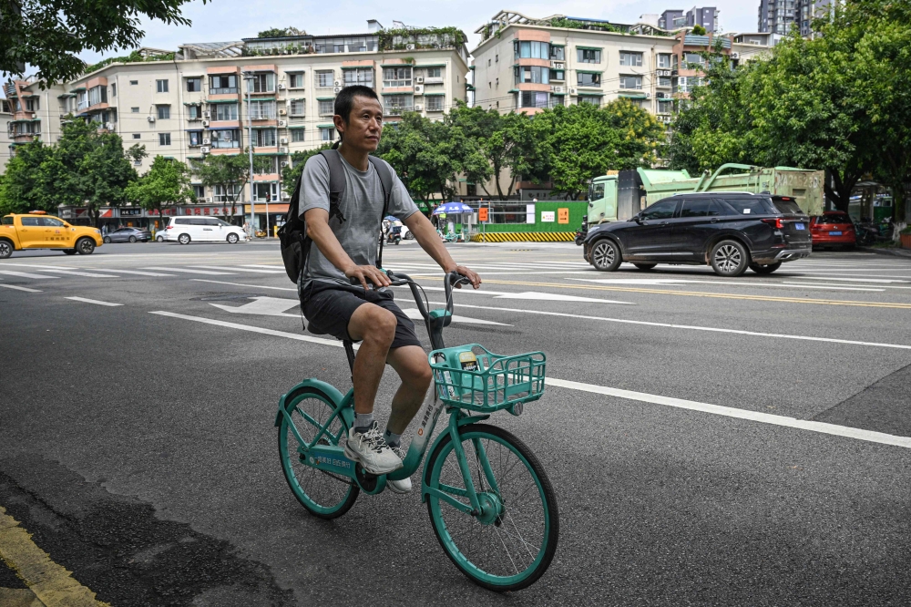 This photo taken on August 18, 2025 shows author Hu Anyan riding a bicycle on a street in Chengdu, in southwestern China's Sichuan province. — AFP pic