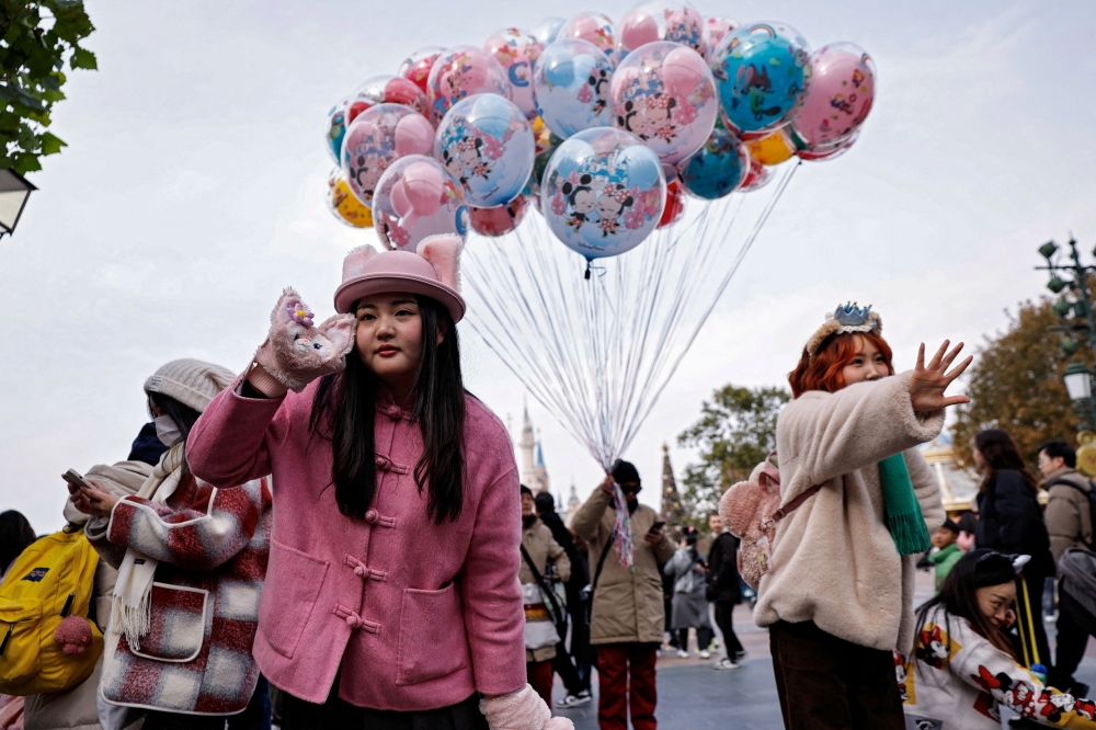 A visitor wearing a hat and a pair of gloves with LinaBell design poses for pictures at Shanghai Disneyland, in Shanghai December 23, 2024. — Reuters pic