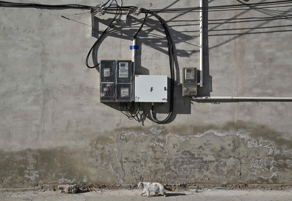 A cat walks under electricity meters in a neighbourhood in Baoding, northern China’s Hebei province on January 7, 2026. — AFP pic
