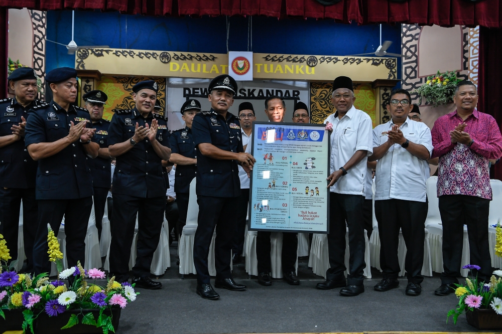 Kedah Police Chief Datuk Adzli Abu Shah hands over an anti-bullying poster to the Principal of Sultan Abdul Hamid College, Rosli Endut on the first day of the 2026 school session January 11, 2026. — Bernama pic