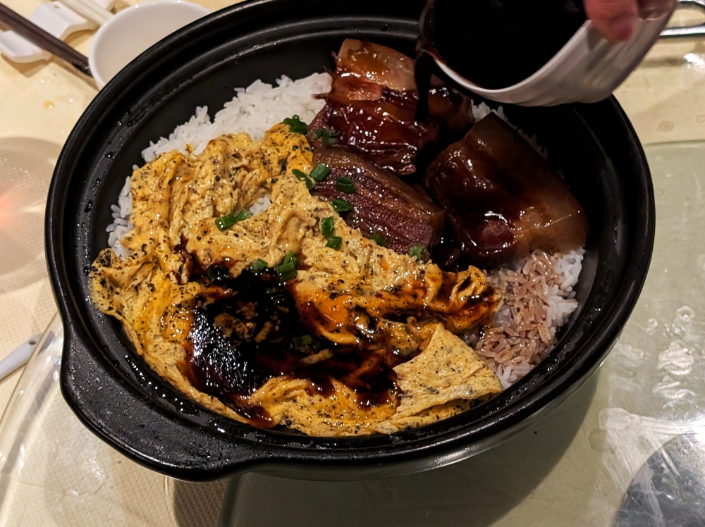 The house-made soy sauce mixture being poured into the Clay Pot Rice with Black Truffle Egg, Lard Crisps & Cured Meat. — Picture by Ethan Lau
