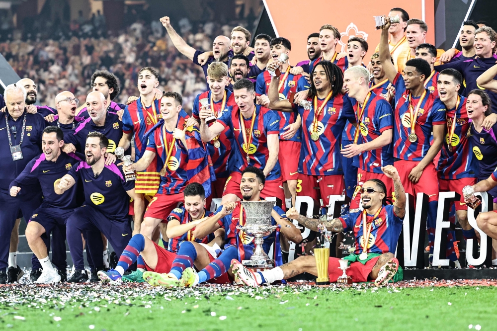 Barcelona’s players celebrate with the trophy after winning the Spanish Super Cup final football match between FC Barcelona and Real Madrid at the King Abdullah Stadium in Jeddah on January 11, 2026.