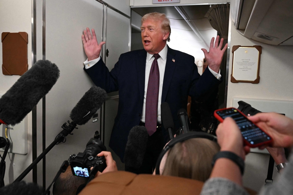 US President Donald Trump speaks to the press aboard Air Force One on January 11, 2026. — AFP pic
