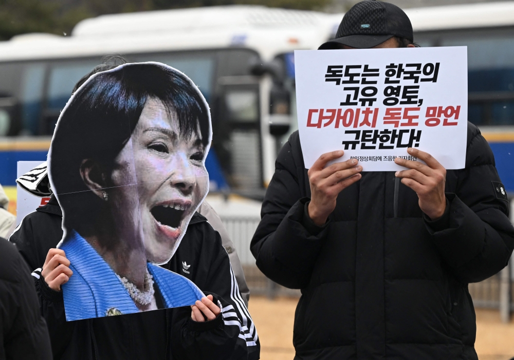 A South Korean activist holds a board-cut of Japan’s Prime Minister Sanae Takaichi next to a placard reading ‘Condemn Takachi’s absurd remarks on Dokdo islets!’ during an anti-Japan protest near the presidential Blue House in Seoul on January 12, 2026, ahead of the South Korea-Japan summit. — AFP pic