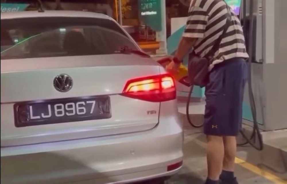 A still shows a Singaporean-registered car with its number plate obscured at a fuel station in Johor Bahru.