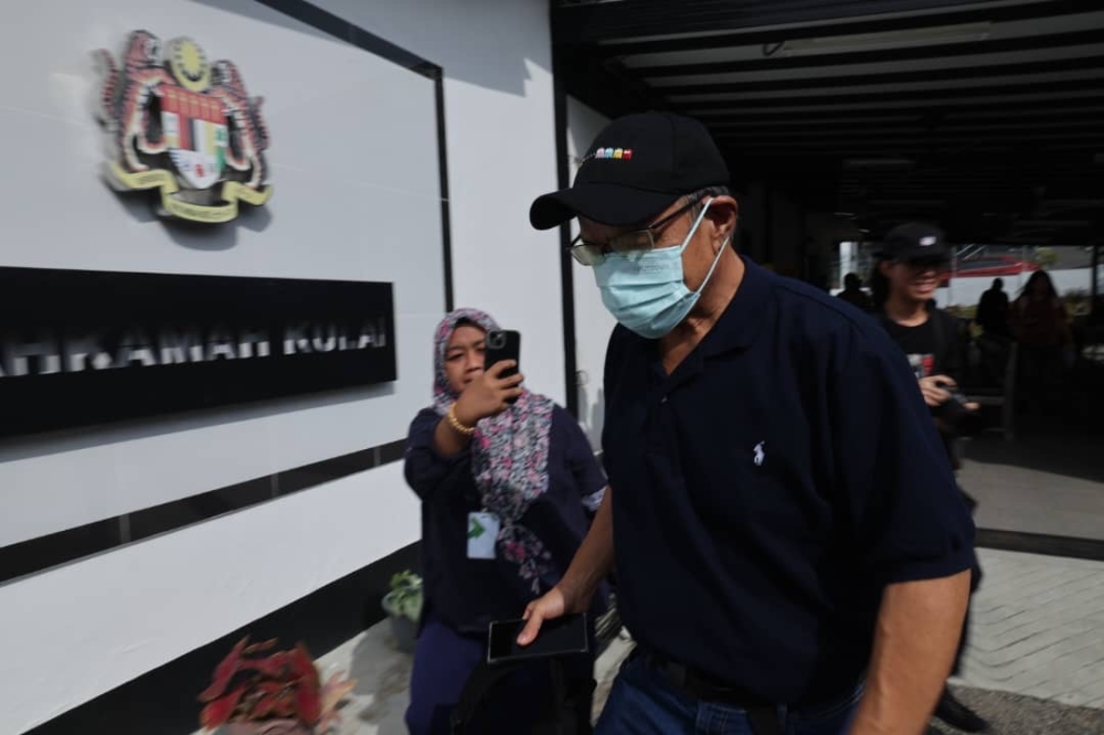 Singapore permanent resident Long Sa Kow (in cap) arrives at the Magistrate’s Court in Kulai on January 14, 2026. — Picture by Ben Tan