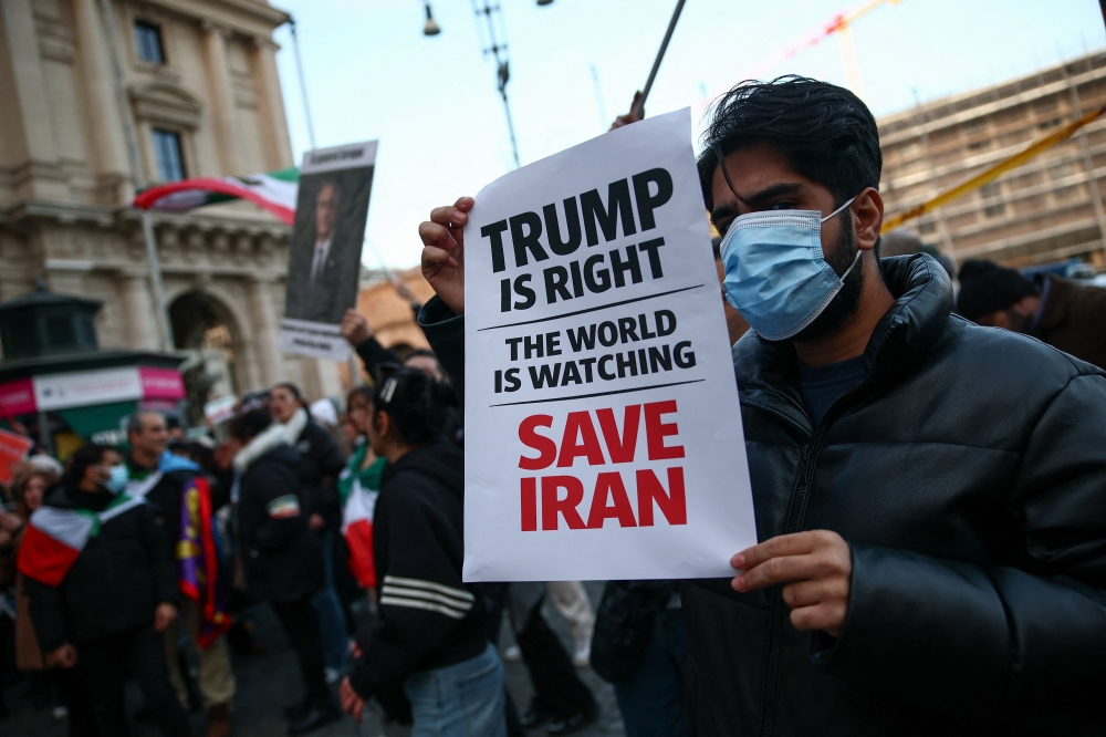 A man shows a sign mentioning US President Donald Trump during a rally in support of nationwide protests in Iran, in Rome January 13, 2026. — Reuters pic
