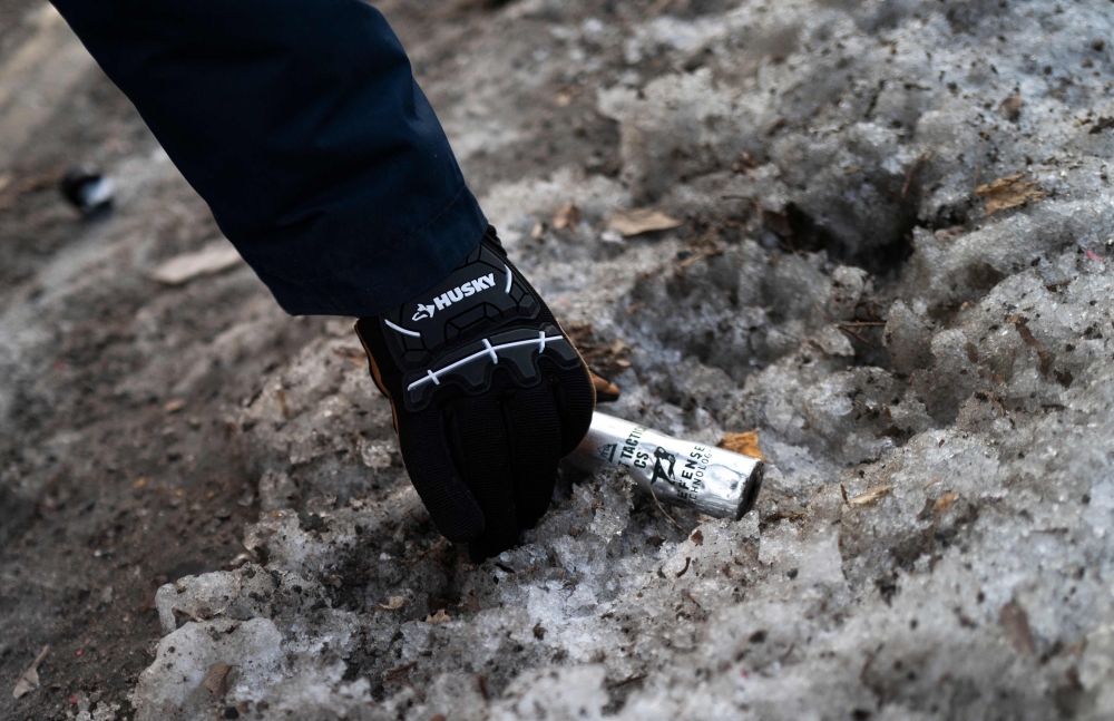 A community member picks up a container of CS gas near the site where a shooting by federal agents occurred last night on January 15, 2026 in Minneapolis, Minnesota. — AFP pic