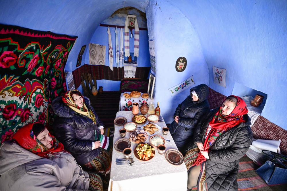Local women wearing traditional Moldovan clothes sit to eat a meal inside a ‘basca’ museum-house in Rogojeni village January 4, 2026. — AFP pic