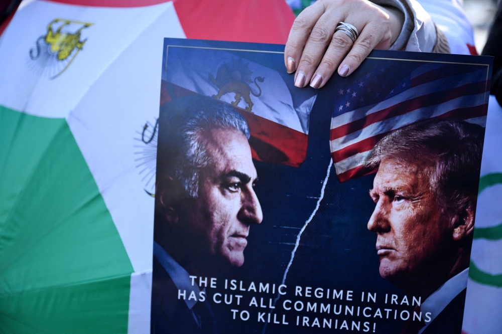 A woman holds up a placard with portraits of the son of the last shah of Iran Mohammad Reza Pahlavi, Reza Pahlavi (left) and US President Donald Trump (right) in front of the US' Consulate General during an anti-Iranian regime rally in Frankfurt am Main, western Germany, on January 16, 2026. — AFP pic
