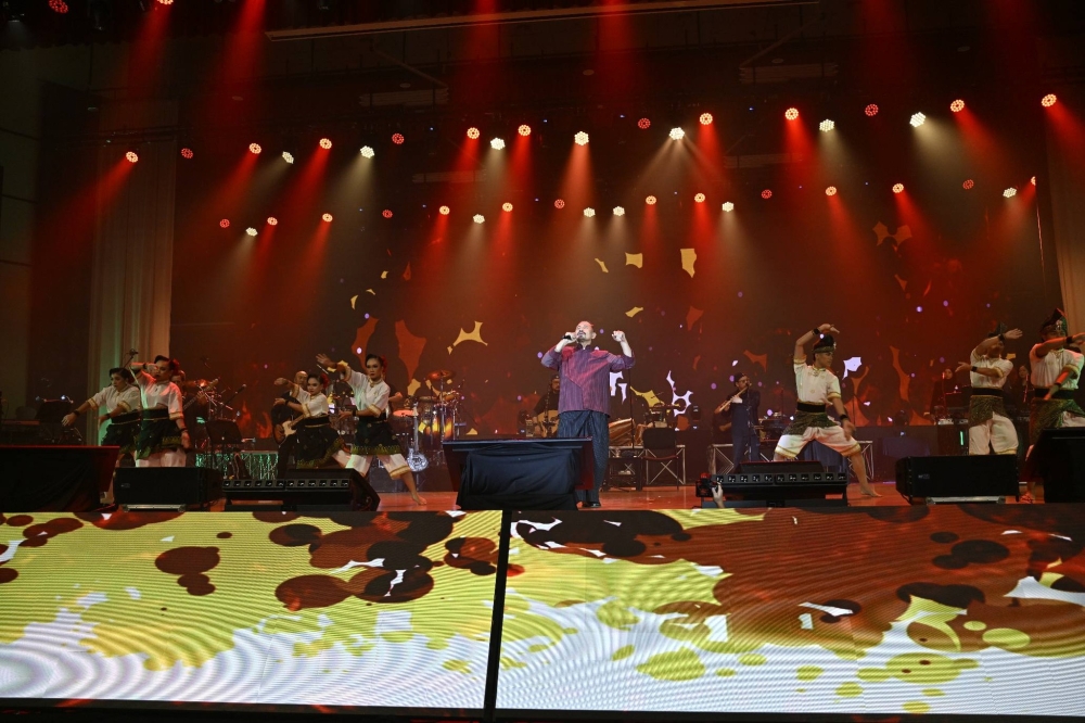 Drumlines, dancers and musicians surround M. Nasir as the ‘Pati Drum’ concept comes alive in a high-energy performance at UPSI. — Picture via Facebook/UPSIMalaysia