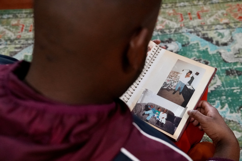 Mohamed Alghali, 33, looks at an album containing photographs of his mother, Rabbiatu Kuyateh, at the home they shared in Bowie, Maryland December 10, 2025. — Reuters pic