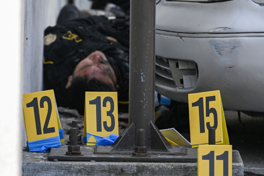 The body of a police officer lies next to evidence markers in the Castanas neighborhood of Villa Nueva, Guatemala, on January 18, 2025. — AFP pic