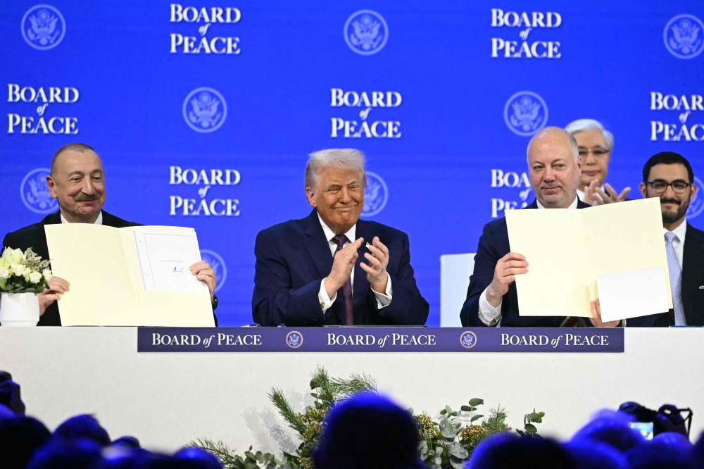 Azerbaijan’s President Ilham Aliyev (L) and Bulgaria’s former Prime Minister Rosen Zhelyazkov (R) hold a signed founding charter as US President Donald Trump applauds at the ‘Board of Peace’ meeting during the World Economic Forum (WEF) annual meeting in Davos on January 22, 2026. — AFP pic
