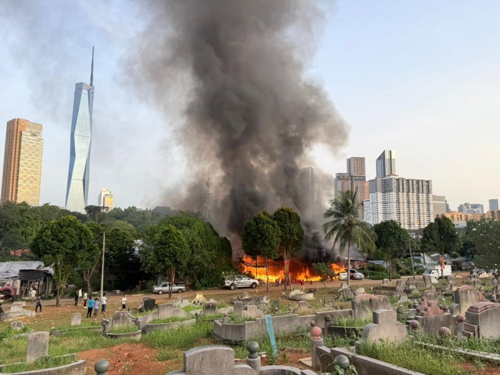 Thick smoke rises from a blaze that destroyed several squatter homes near the Nirvana burial grounds on Jalan Bellamy this morning. — Bomba pic