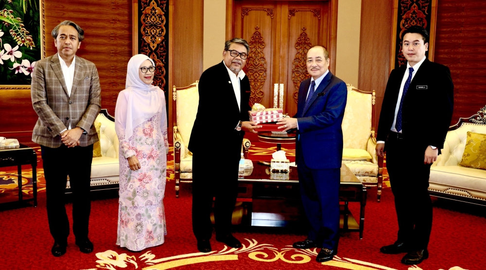 Hajiji (2nd right) presents a memento to Ahmad Jailani. — The Borneo Post pic