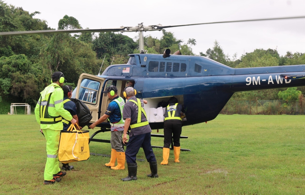EC personnel and police officers board a helicopter at the Penampang Municipal Council field en route to remote polling stations in Sabah November 28, 2025. Similar deployments were carried out today in Kinabatangan, where helicopters delivered ballot boxes to three hard-to-reach centres ahead of Saturday’s vote. — Bernama pic